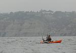 C. Cary gaffing a Yellowtail of La Jolla. Blacks Beach in background.